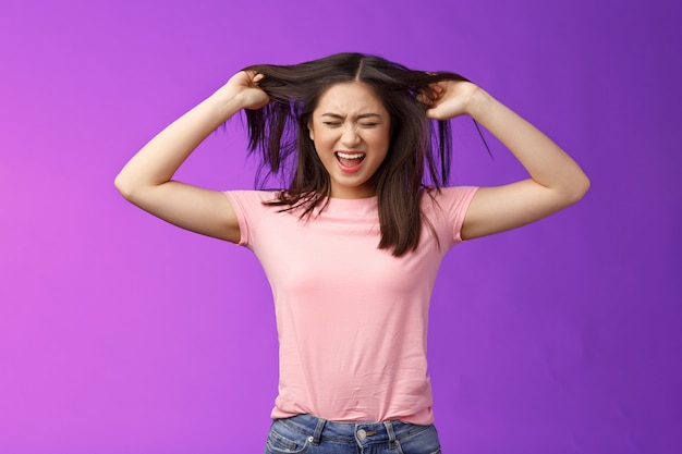 Upset distressed asian brunette girl frowning screaming, pull out hair fed up poor haircare, disappointment weak strands, stand purple background annoyed, pissed complain hairsalon.