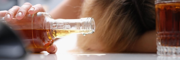 Upset drunk woman with bottle of alcohol closeup