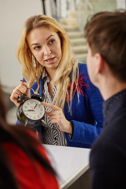 An upset female boss points a time to a subordinate