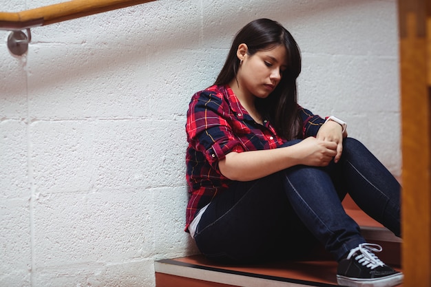 Upset female student sitting on staircase