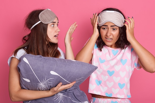 Upset friends girl in night suit for a pajama party on pink background