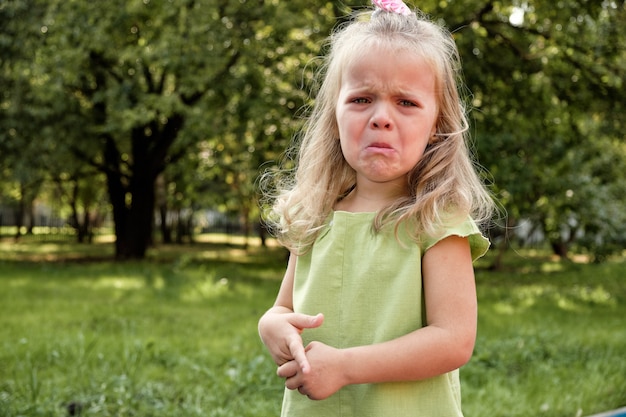 Upset girl child crying in the park. Parenting, child psychology.