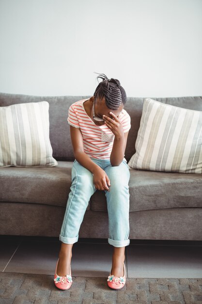 Upset girl sitting on chair in corridor