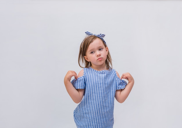 Upset little girl in a striped blouse on a white isolated