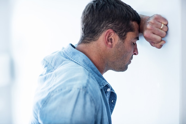 Upset man leaning on wall