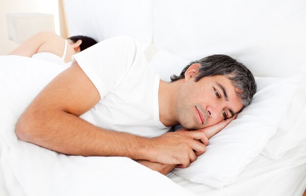 Photo upset man lying in his bed