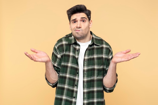 Upset man making a hand gesture showing doubt through facial expression isolated yellow background