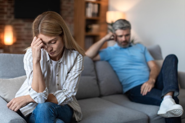 upset middle aged caucasian male with beard ignores offended lady after conflict in living room interior