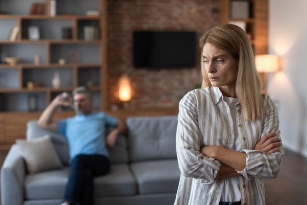 Upset offended middle aged caucasian wife ignores angry sad husband in living room interior Conflict stress