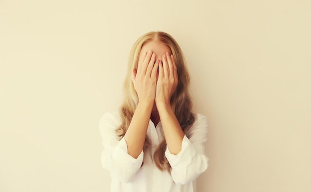 Upset sad crying young woman covering her eyes with her hands while experiencing mental