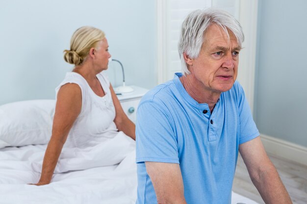 Upset senior couple sitting on bed