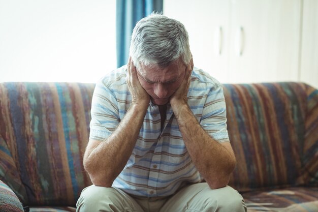 Upset senior man sitting in living room