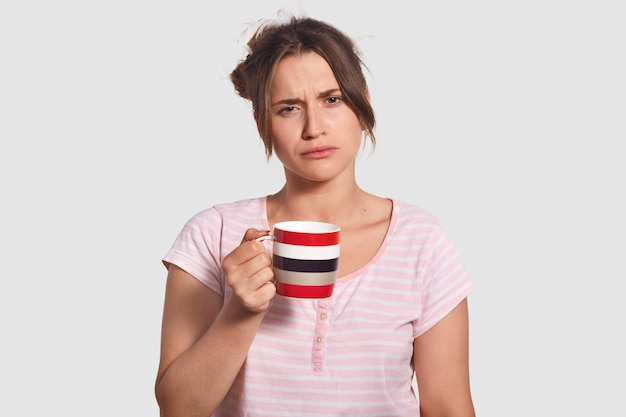 Upset sleepy lovely young woman holds cup of coffee