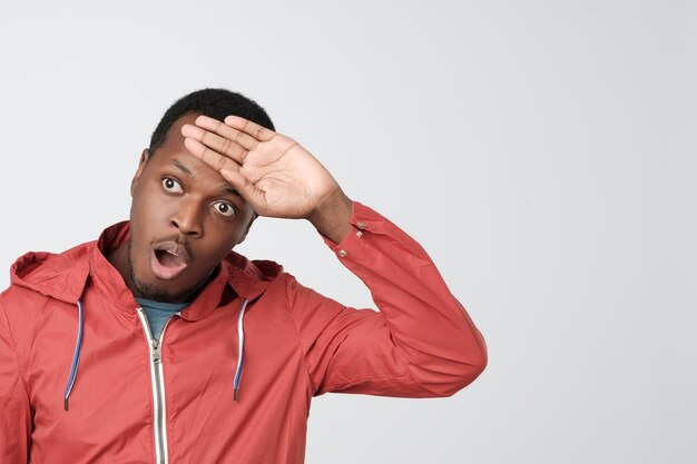 Upset and tired handsome african american in red jacket whiping sweat out of forehead