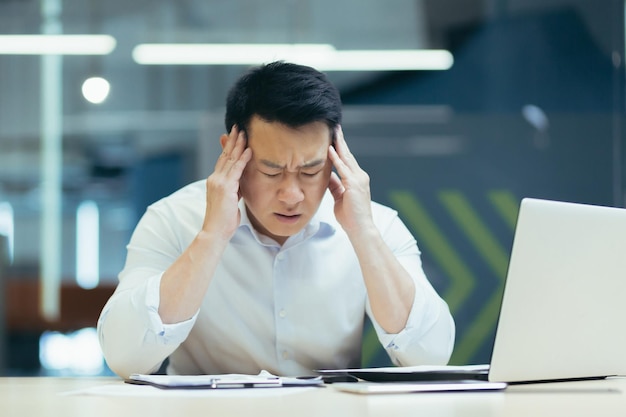 Upset and unhappy asian businessman reading documents and letter from bank businessman at work in