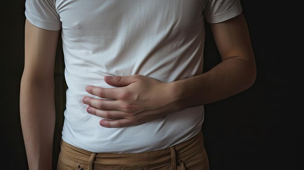 Photo upset unhappy young man holding his abdomen with both hands suffering from bellyache isolated on gray background