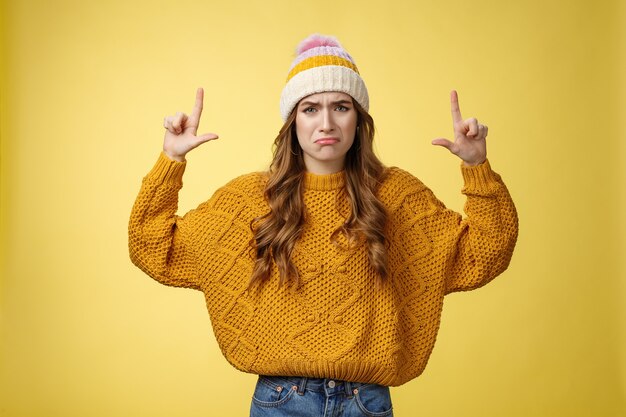 Upset whining complaining displeased cute young immature girl raise hands pointing up crying jealous regret wanna buy cool product have no money, standing sad sobbing yellow background