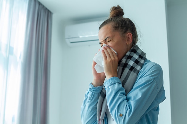 Photo upset woman caught a cold from the air conditioner and sneezing