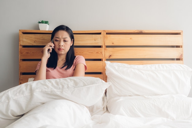 動揺している女性は彼女のベッドで電話での会話をしています。