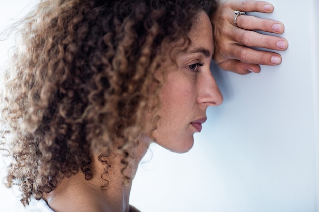 Upset woman leaning on wall