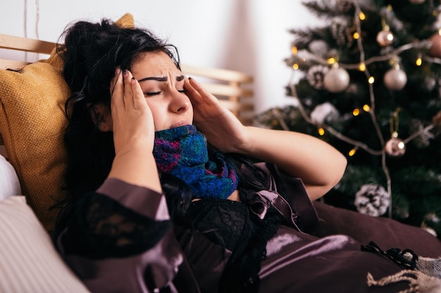 Upset woman lying in bed with fever and high temperature