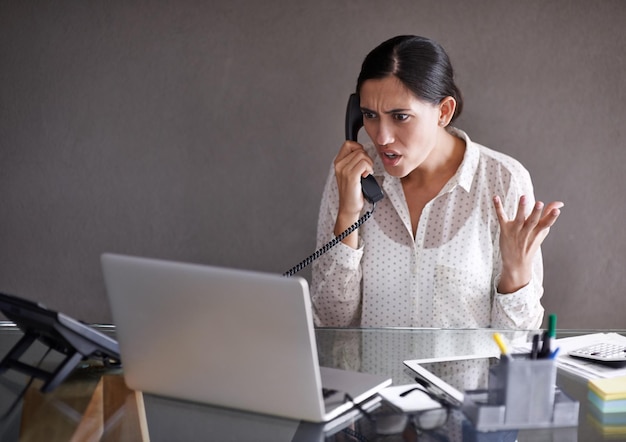 Upset woman and phone call in home office for conversation on work frustrated and speaking on business for networking Person annoyed and discussion on startup company with laptop for research