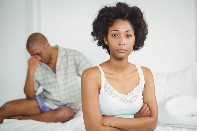 Upset woman sitting on bed after arguing with her boyfriend