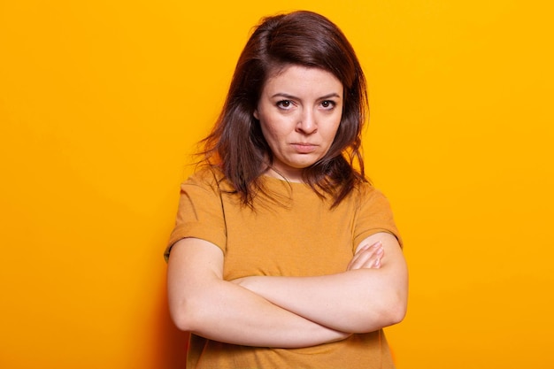 Upset woman standing with crossed arms in studio