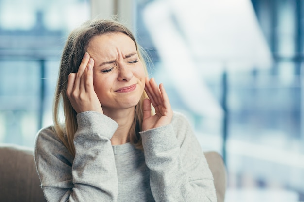  upset woman with closed eyes blonde touching temples suffering from headache 