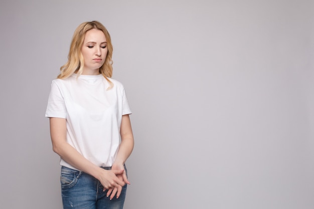 Foto giovane bella donna turbata che sta con le mani attraversate isolate al fondo bianco dello studio