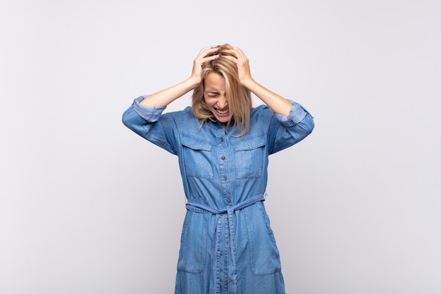 Foto giovane donna graziosa bionda turbata con il vestito dal jeans