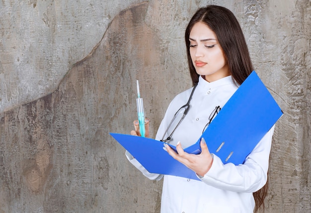 An upset young doctor looking check list while holding inject