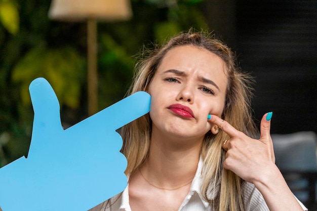 Upset young lady put her finger to her face and looking at the camera