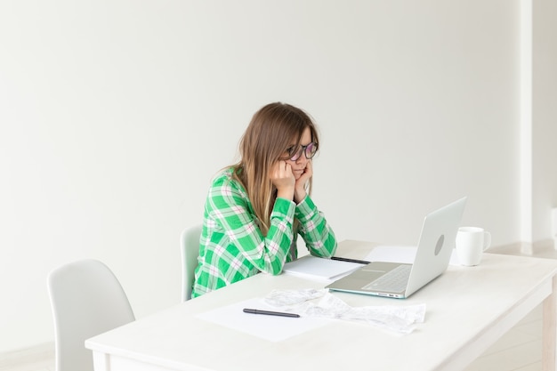 Upset young woman considers the amount of expenses for purchases and payment of credits by entering information into laptop for accounting of home bookkeeping. Concept of savings and waste