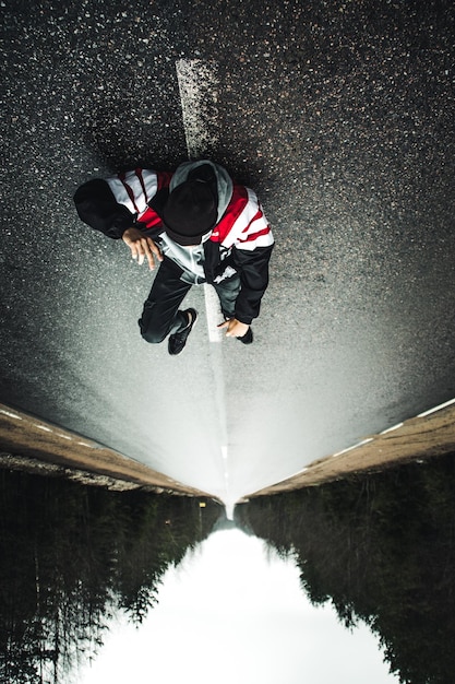 Upside down image of man lying on road in forest