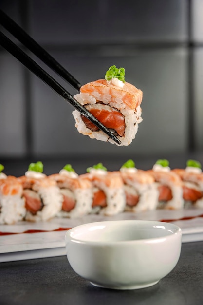 Uramaki steekvlam zalm op stokjes met sojasaus. Detailopname.