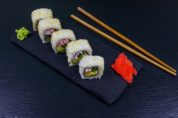 Uramaki sushi rolt met surimi op een zwarte lei