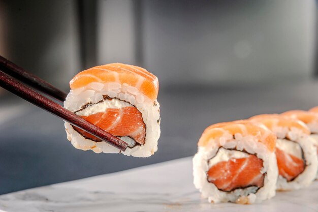 Uramaki-zalm op eetstokjes. Detailopname.