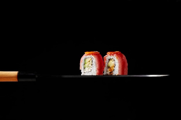 Uramakibroodjes met tonijnroomkaas, avocado en kumquatplakken op blad van Japans sashimimes