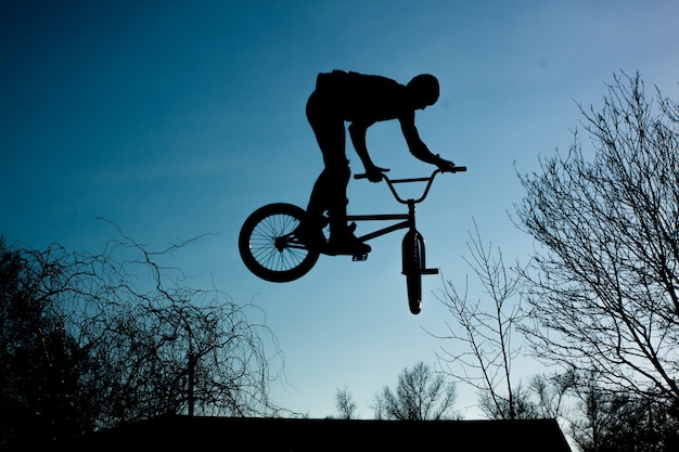 Urban athlete biker performing acrobatic jump. Guy riding bmx bicycle at extreme sport competition. Alternative lifestyle concept.