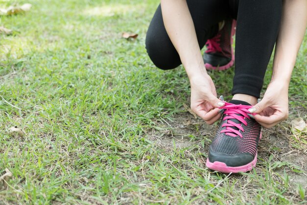 Urban athlete woman tying running shoe laces.