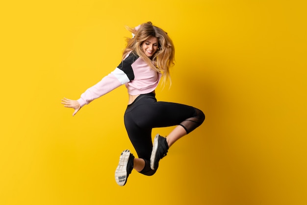 Urban Ballerina dancing over isolated yellow  and jumping