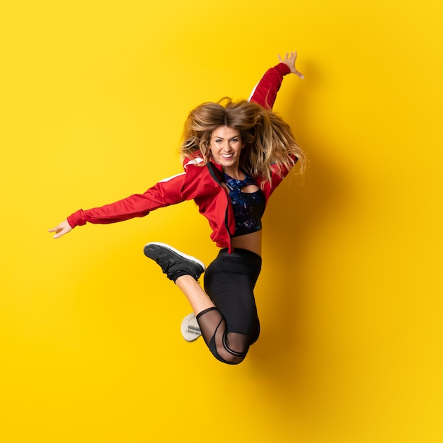 Urban Ballerina dancing over isolated yellow  and jumping