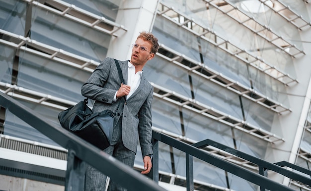 Urban beauty Young businessman in grey formal wear is outdoors in the city