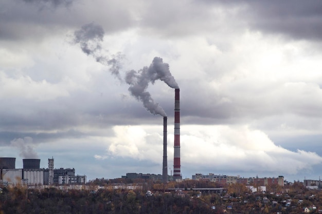 Paesaggio urbano nuvoloso tubi urbani che fumano un'area industriale che illustrano l'inquinamento e i danni alla produzione