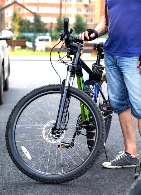 An urban cyclist stands next to a bicycle. environmentally\
friendly transport.