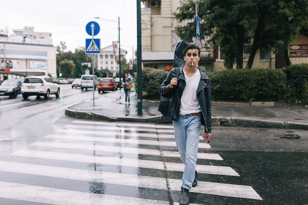 Foto uomo di stile rock fiducioso di moda urbana che cammina con la chitarra. concetto di vita di città di stile di vita musicale