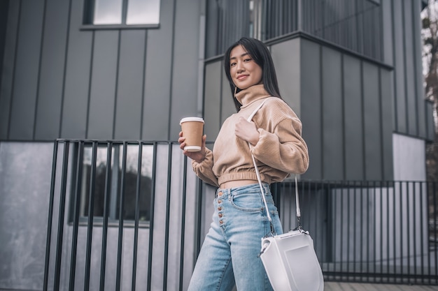 Urban fashion. Trendy asian young woman standing outdoors and looking good