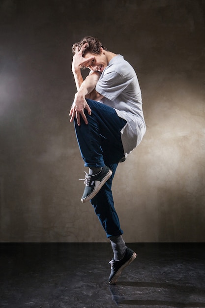 Urban hip hop dancer with grunge concrete wall background texture jumping and dancing