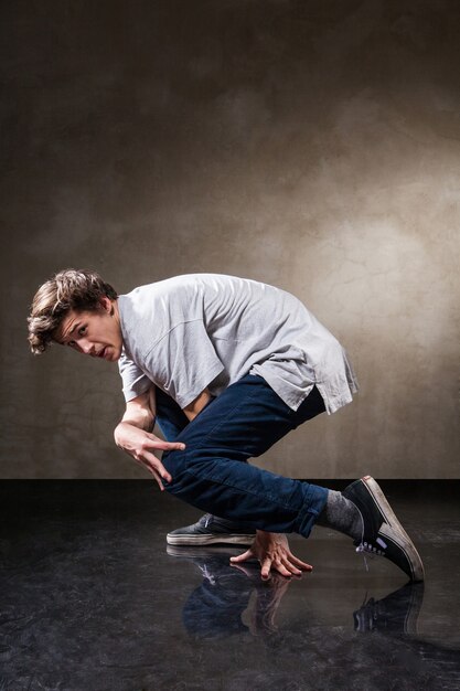 Urban hip hop dancer with grunge concrete wall background texture jumping and dancing